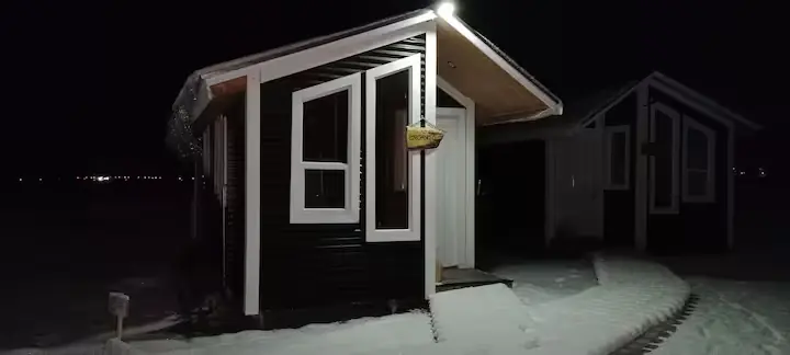 Cabaña Encanto iluminada durante una noche nevada de invierno en Puerto Natales, Patagonia chilena