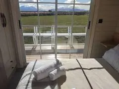 Dormitorio matrimonial de Cabaña Magia con vista panorámica desde la cama hacia la terraza y cordillera