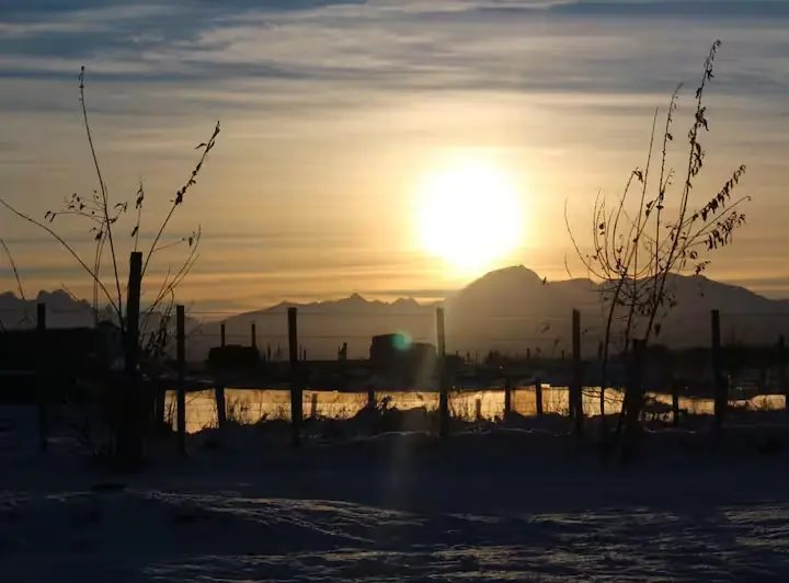 Amanecer invernal sobre la cordillera nevada y laguna escarchada vista desde el entorno de las cabañas en Puerto Natales